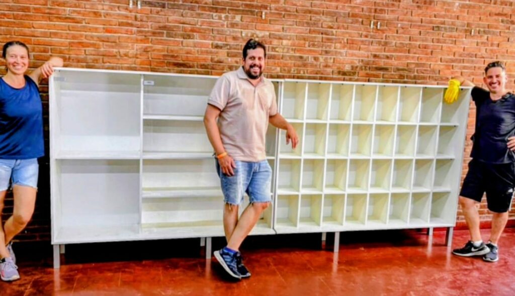 Una madre y dos padres, felices y cansados, posan frente al armario, se aprecia que la altura del mismo llega a los hombros de una persona adulta.